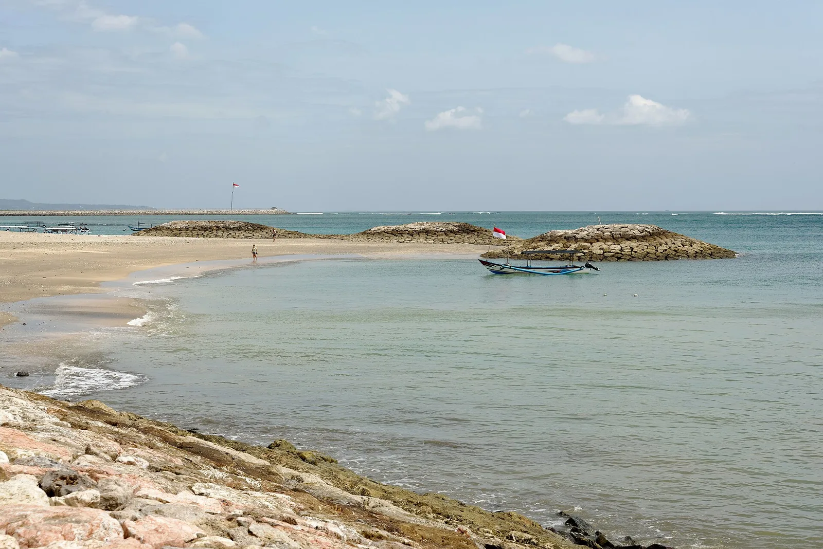 רחוב תוסס ומלא חיים בקוטה בדרום באלי עם חנויות, שלטי ניאון ותיירים בשעות הערב המוקדמות